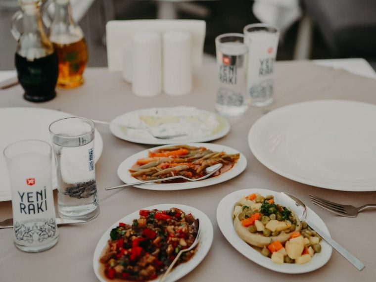 From above of served table with assorted delicious appetizers with beverages and dishware on veranda of restaurant in evening