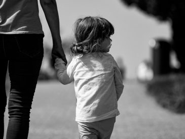 A woman holding the hand of a small child