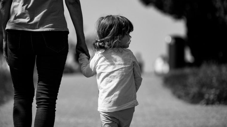 A woman holding the hand of a small child