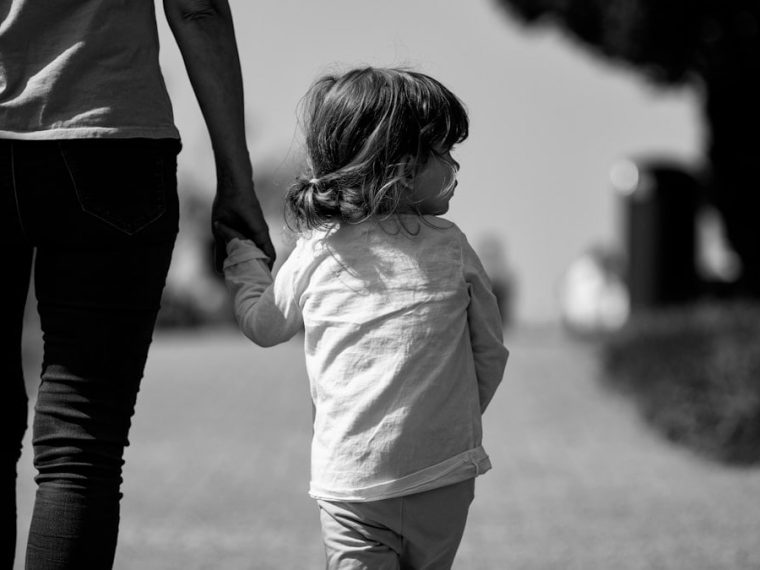 A woman holding the hand of a small child